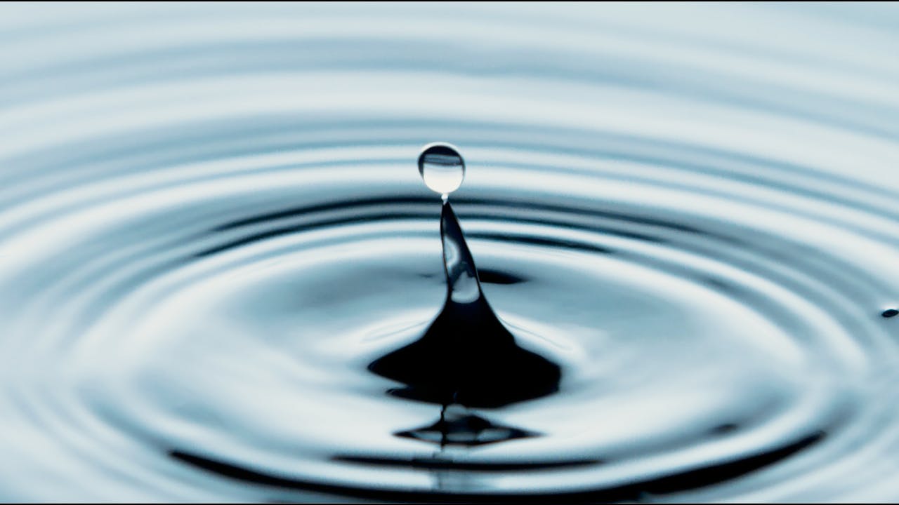 Captivating close-up of a water drop splash creating ripples, perfect for backgrounds.